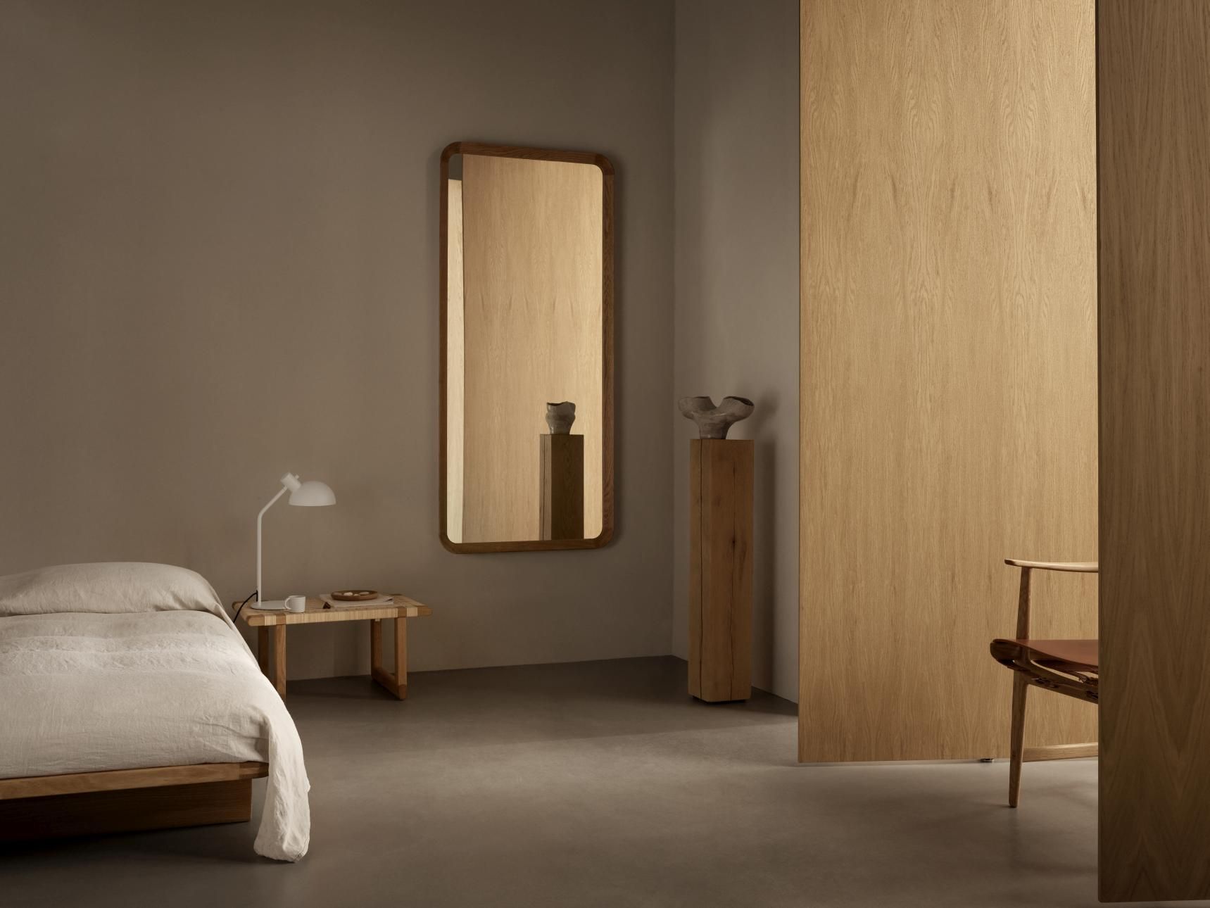 VLA62 Radio House Spiegel von Carl Hansen in Schlafzimmer mit Bett und Lampe.