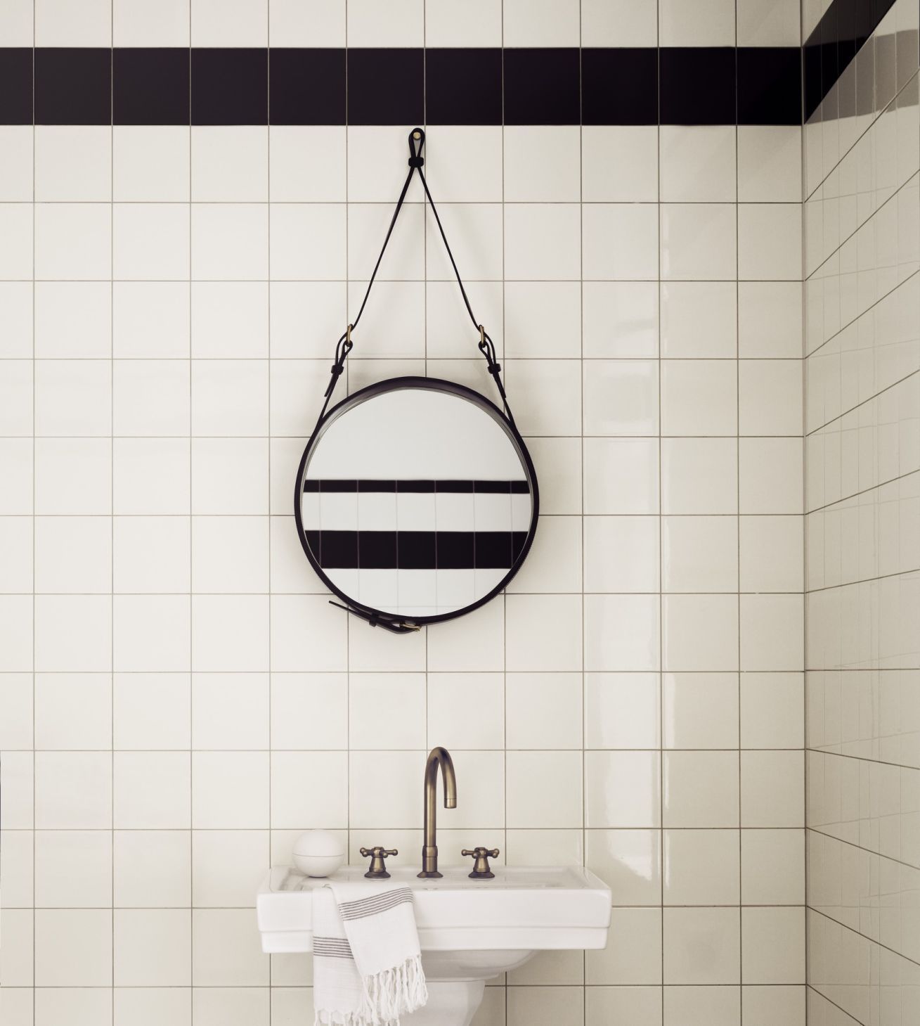 Adnet Circular Spiegel von Gubi im Badezimmer mit Waschbecken und weißen Fliesen.
