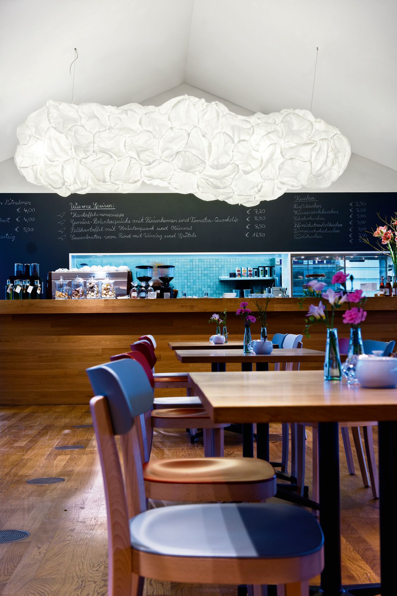 Helle Mamacloud LED Pendelleuchte von Belux über Tischen in einem Restaurant.