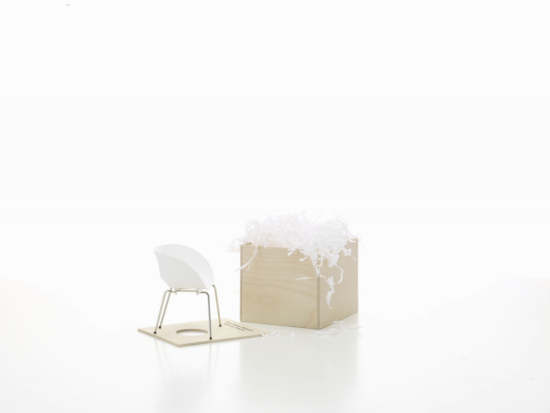 Vitra Tom Vac Miniatur Stuhl [1999] mit weißer Sitzschale und Holzbox mit Füllmaterial.