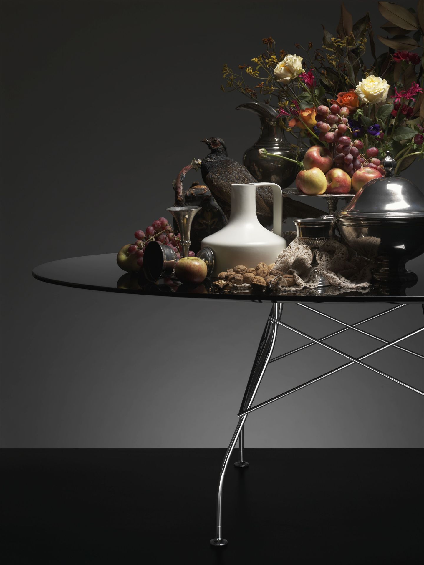 Schwarzer, runder Kartell Glossy Tisch mit Marmor-Steinzeug-Optik, dekoriert mit Blumen, Obst und Nüssen.