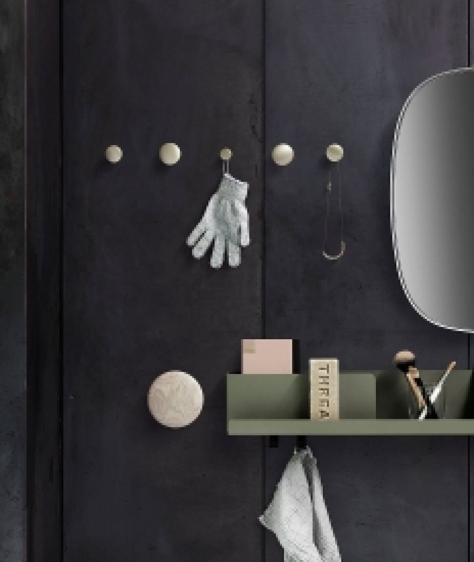 Schwarzes Muuto Folded Shelves Wandregal 51x22 cm an dunkler Wand mit Dekoration und Spiegel.