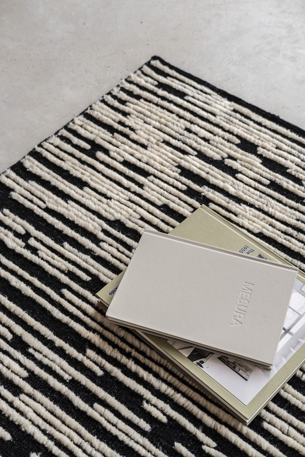 Detailaufnahme des Nanimarquina Teppichs Doblecara Rug in Schwarz und Weiß mit Büchern.