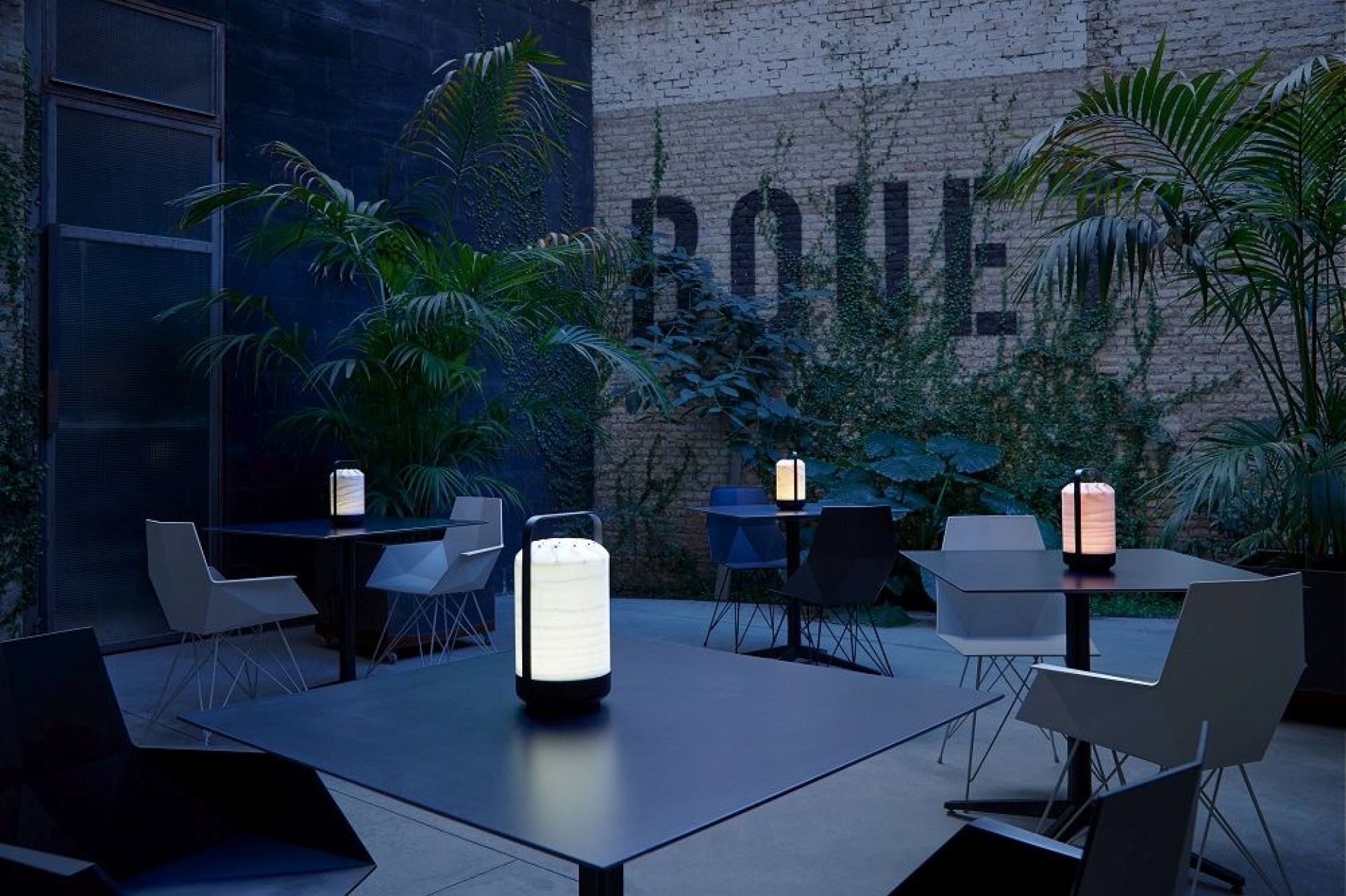 Chou Mini LED Akkuleuchte von LZF Lamps auf Tischen in einem Außenbereich.