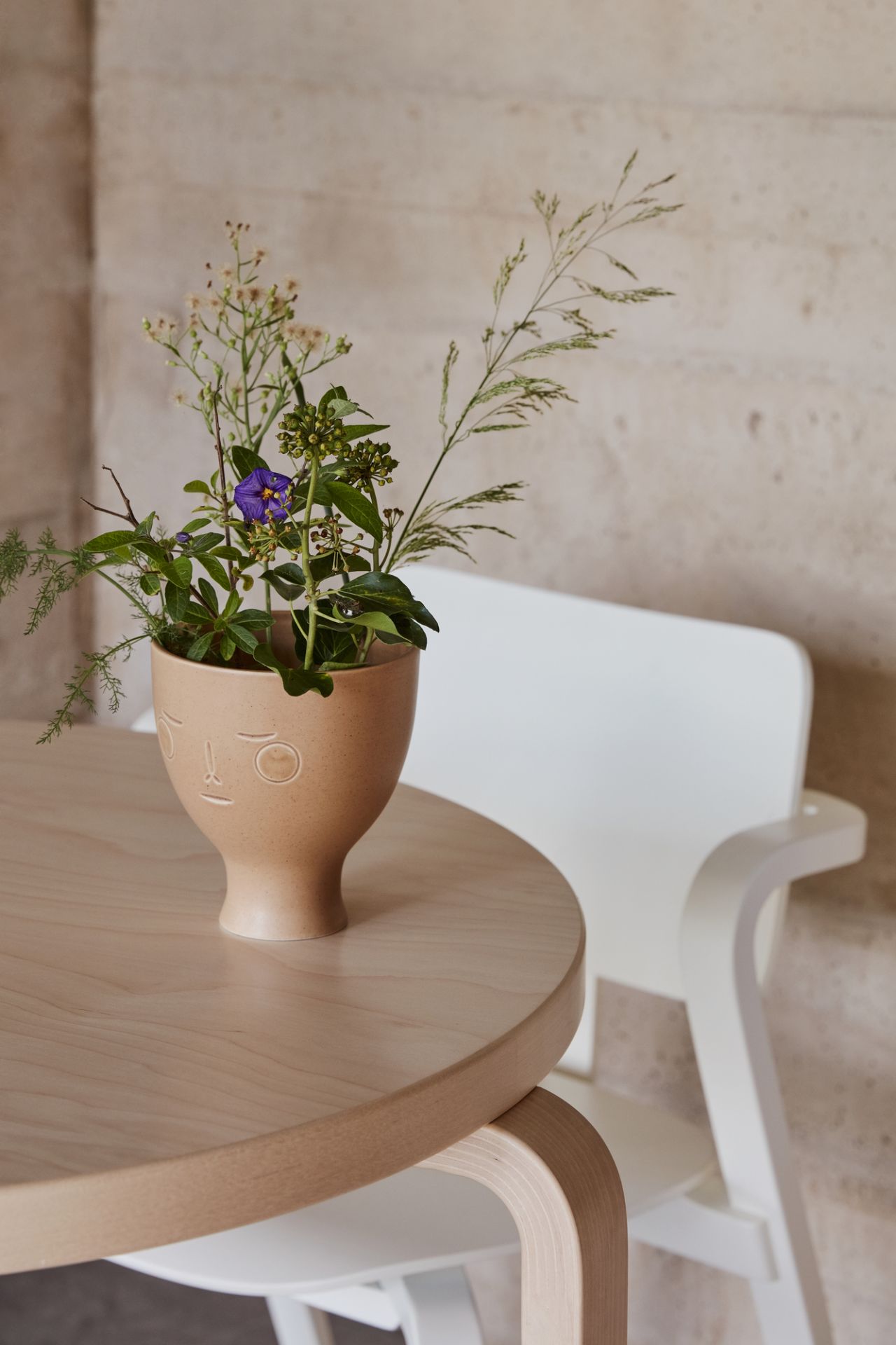 Nahaufnahme von einem Artek Stuhl, Modell Aslak Chair, mit Holztisch und Blumenvase.