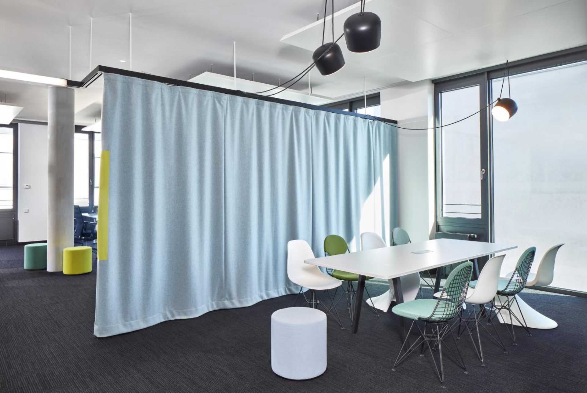 Büro mit Konferenztisch und verschiedenen Stühlen, darunter ein mintfarbener Panton Chair von Vitra.