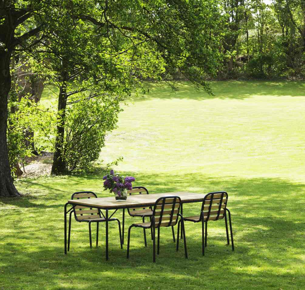 Normann Copenhagen Vig Table Gartentisch mit Stühlen auf Rasenfläche, ideal für entspannte Stunden im Freien.