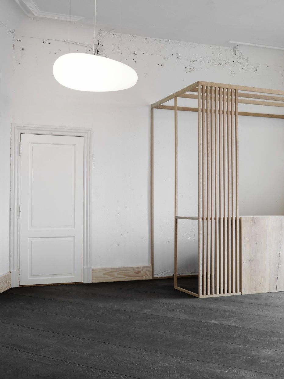 Weiße Avion Pendelleuchte von Fritz Hansen im minimalistischen Raum mit Holzelementen und dunklem Boden.