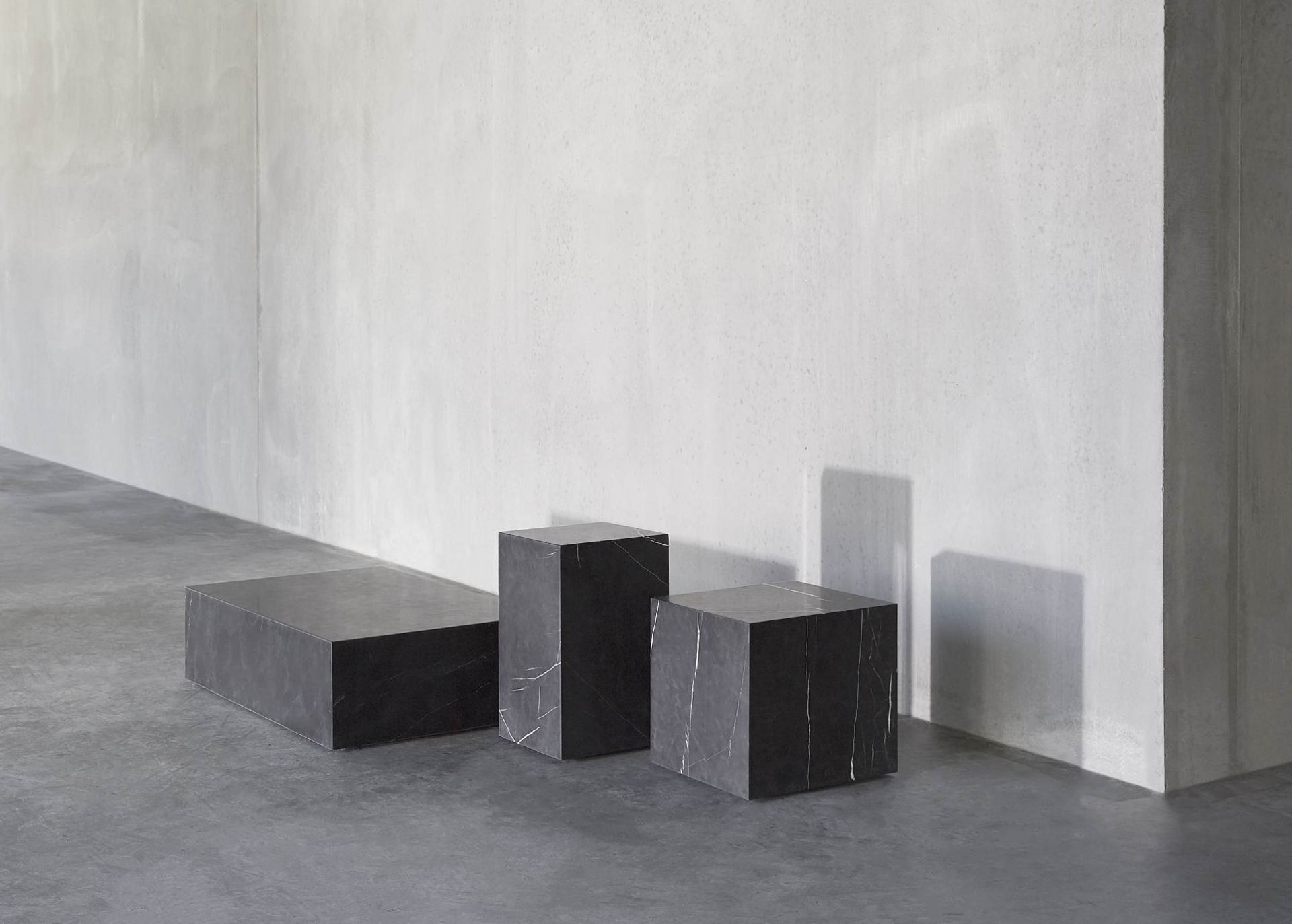 Audo Copenhagen Plinth Tisch Konfiguration mit drei schwarzen Marmor Podesten in verschiedenen Höhen.
