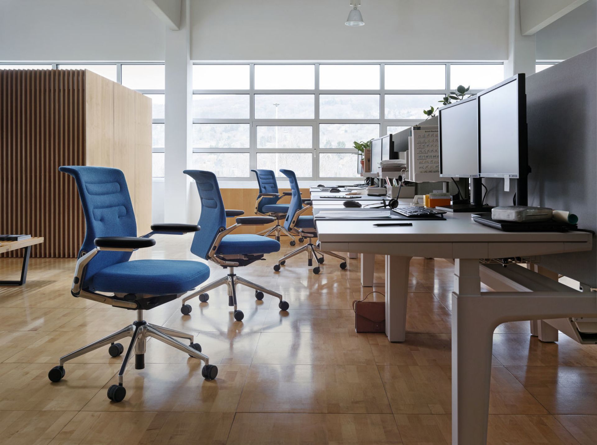 Büro mit mehreren blauen AC5 Work Drehstühlen von Vitra mit verstellbarer Lumbalstütze und Chromfußkreuz.