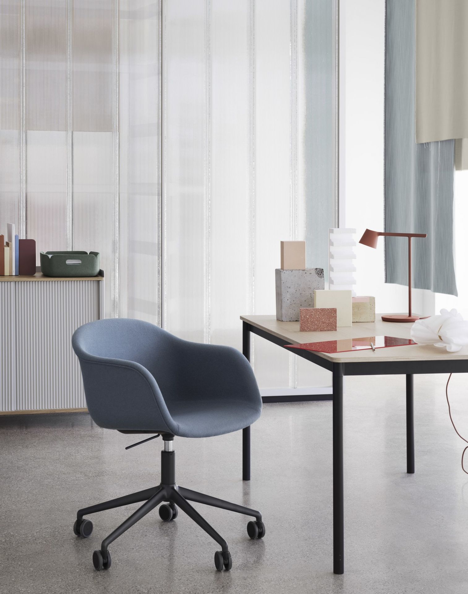Blauer Bürostuhl vor Muuto Enfold Sideboard und Schreibtisch mit Lampe im modernen Büro.