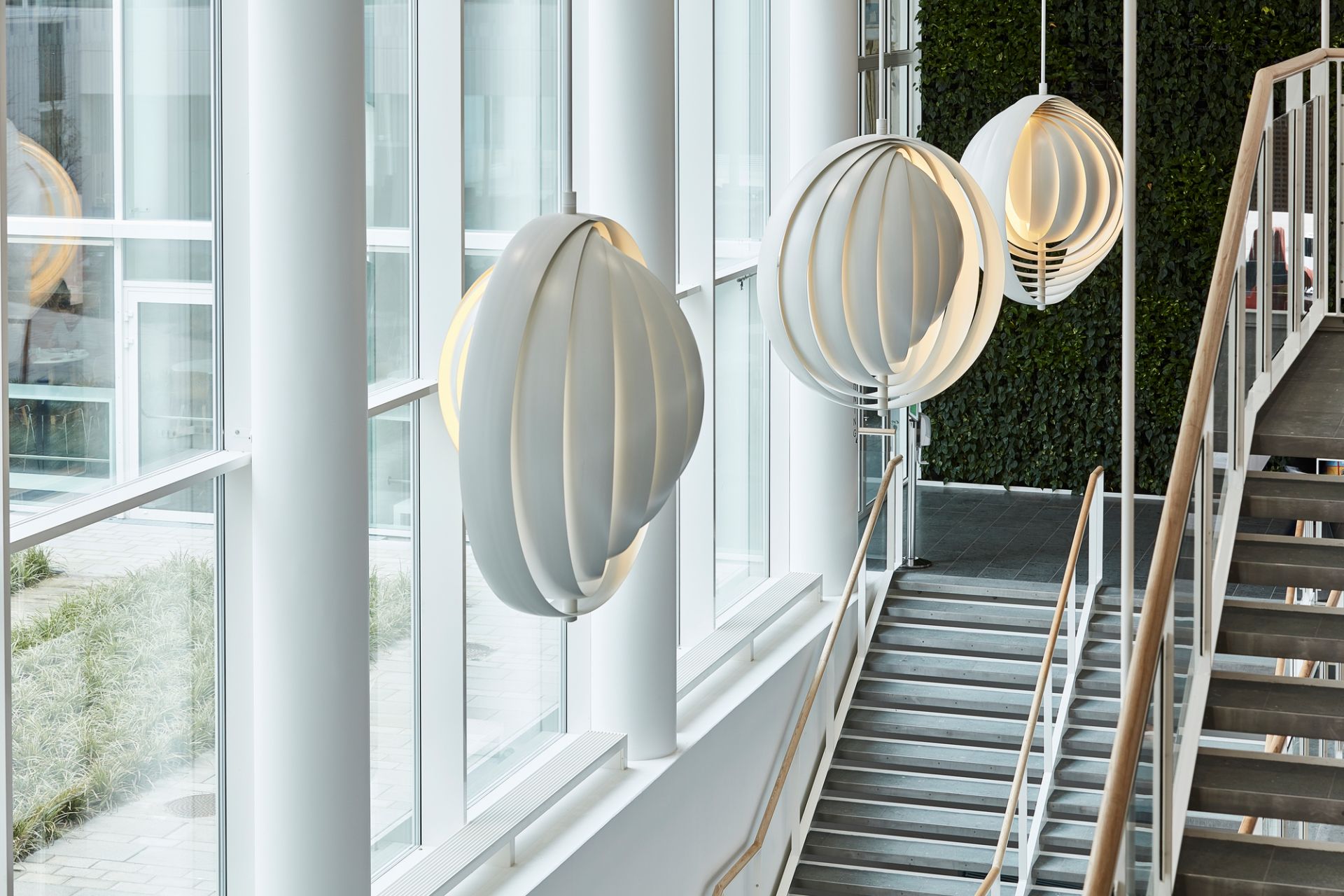 Drei weiße Verpan Moon Pendelleuchten im Treppenhaus, modernes Design, stimmungsvolle Beleuchtung.