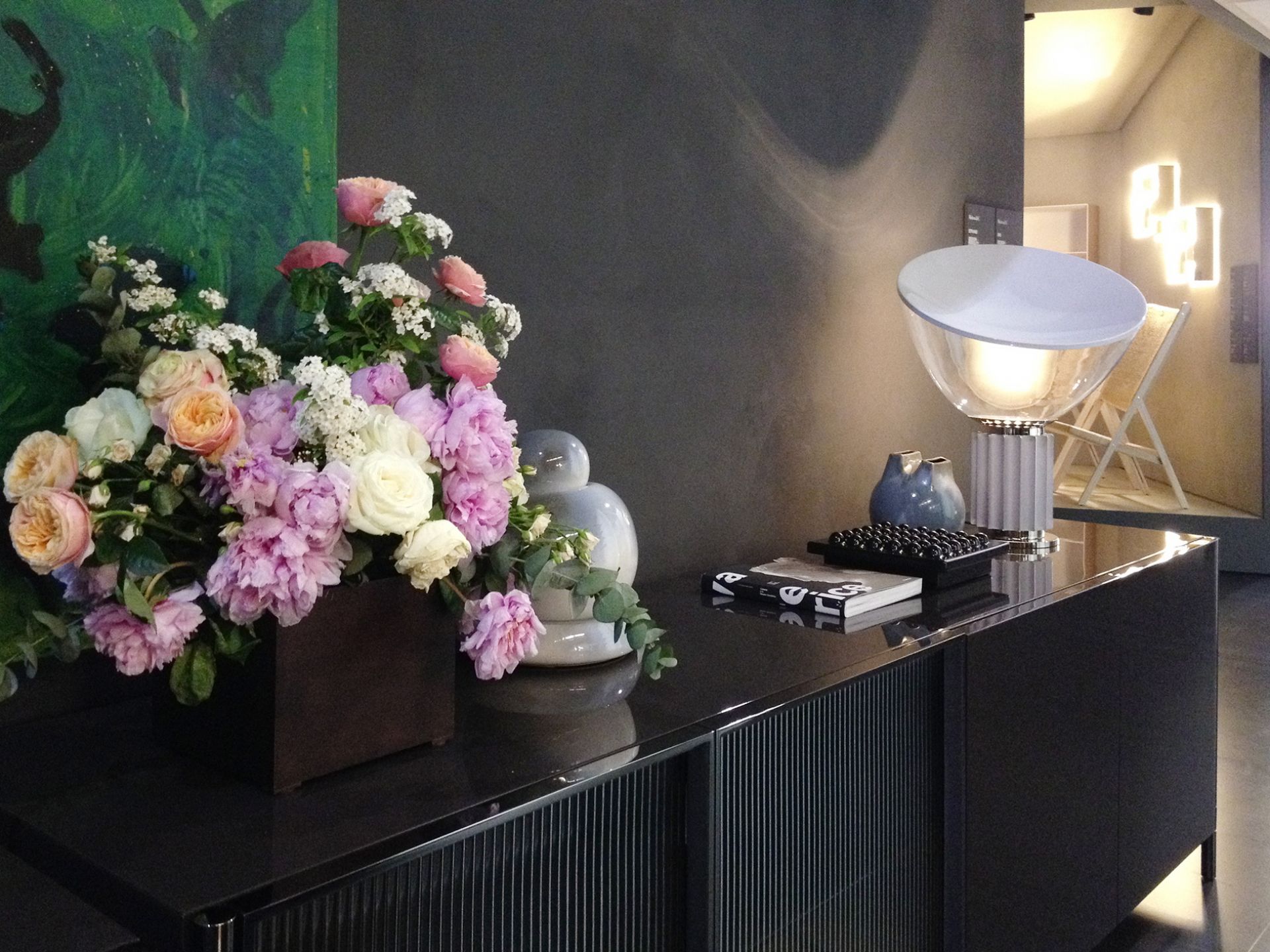 Taccia Tischleuchte von Flos auf einem Sideboard, umgeben von Blumen und dekorativen Objekten.