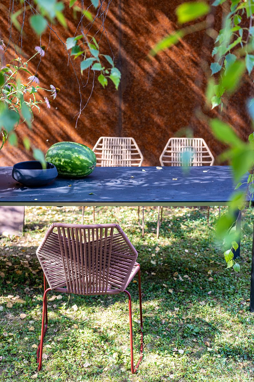 Nahaufnahme eines braunen Tropicalia Outdoor Stuhls von Moroso auf einer grünen Wiese.