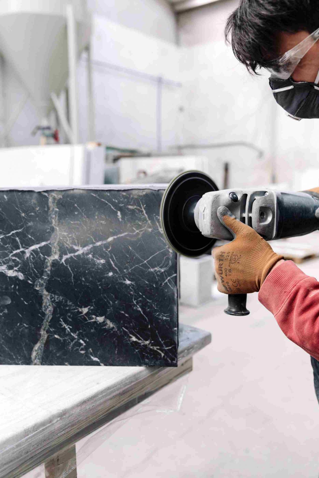 Audo Copenhagen Plinth Tisch: Handwerker poliert Marmorplatte für modernen Couchtisch.