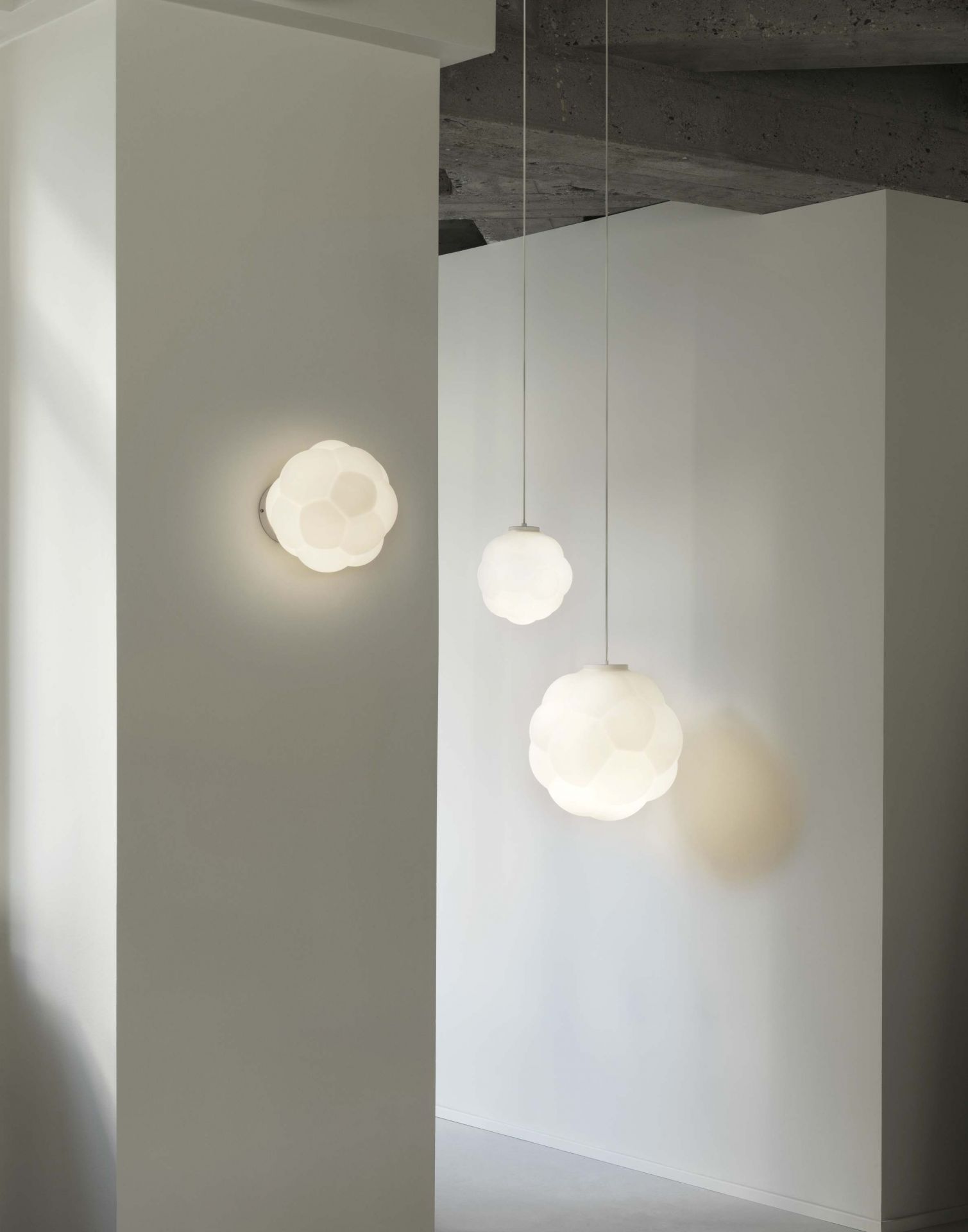 Nahaufnahme von zwei Bubba Pendelleuchten von Normann Copenhagen, hängend und an der Wand montiert.