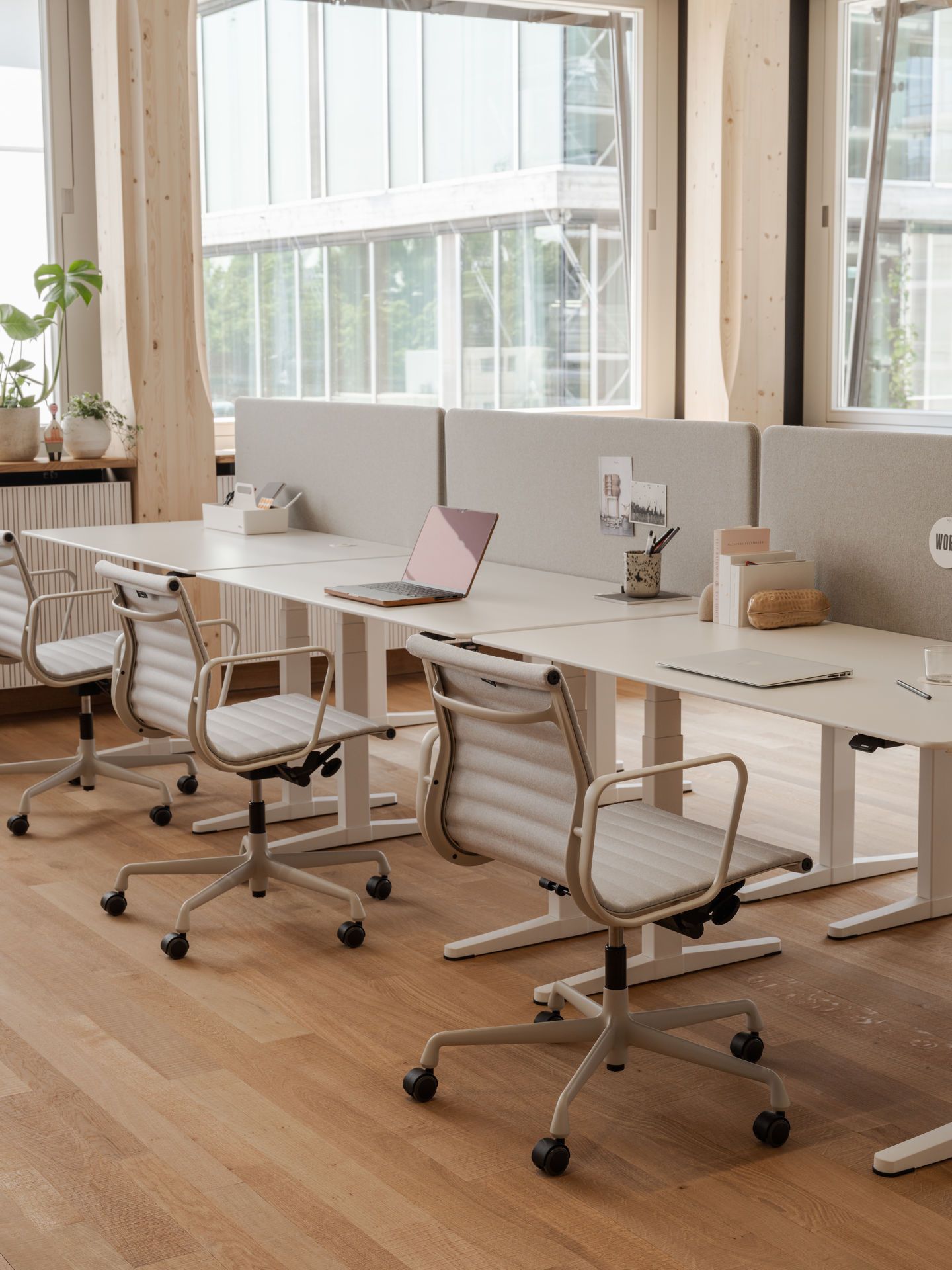 Vitra Aluminium Chair EA 118 in beigem Leder auf Rollen vor Bürotischen im modernen Büro.