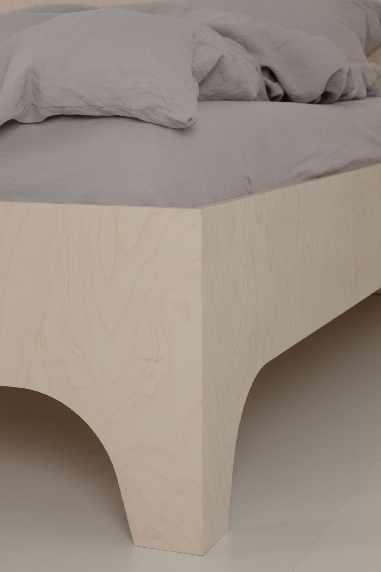 Detailaufnahme von VALENTINA Bett mit hellem Holzrahmen und grauer Bettwäsche, modernes Schlafzimmer Design.