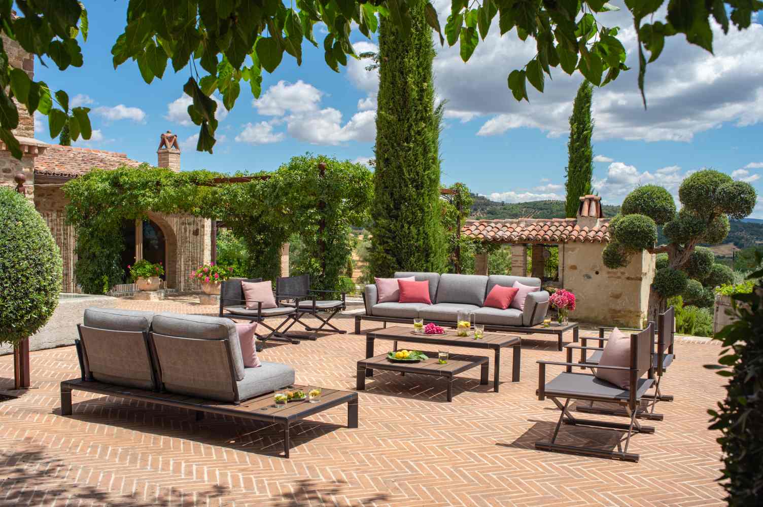 Emu Terra Lounge Möbelset auf einer Terrasse mit Sessel, Sofa und Tischen für den Außenbereich.