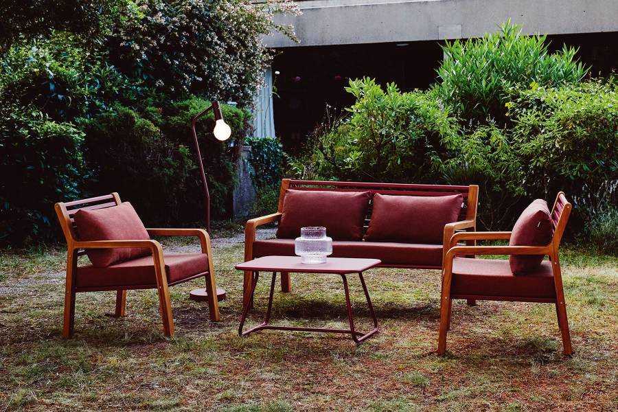 Somerset Sofa von Fermob: Outdoor-Sitzgruppe mit Sofa, Sesseln und Tisch in Gartenumgebung.