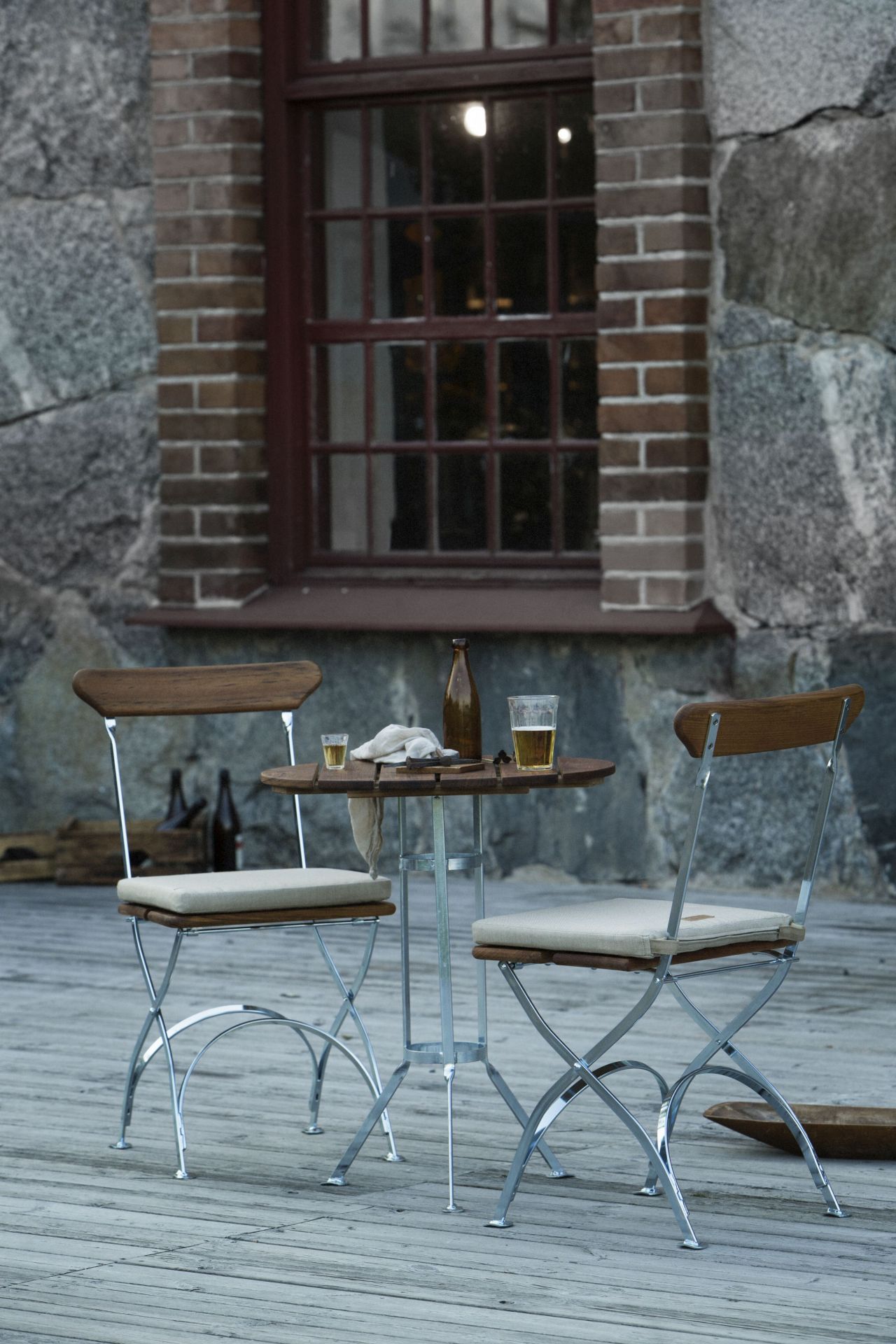Zwei Grythyttan Stühle aus Eiche mit Tisch auf einer Holzterrasse, ideal für Garten und Balkon.