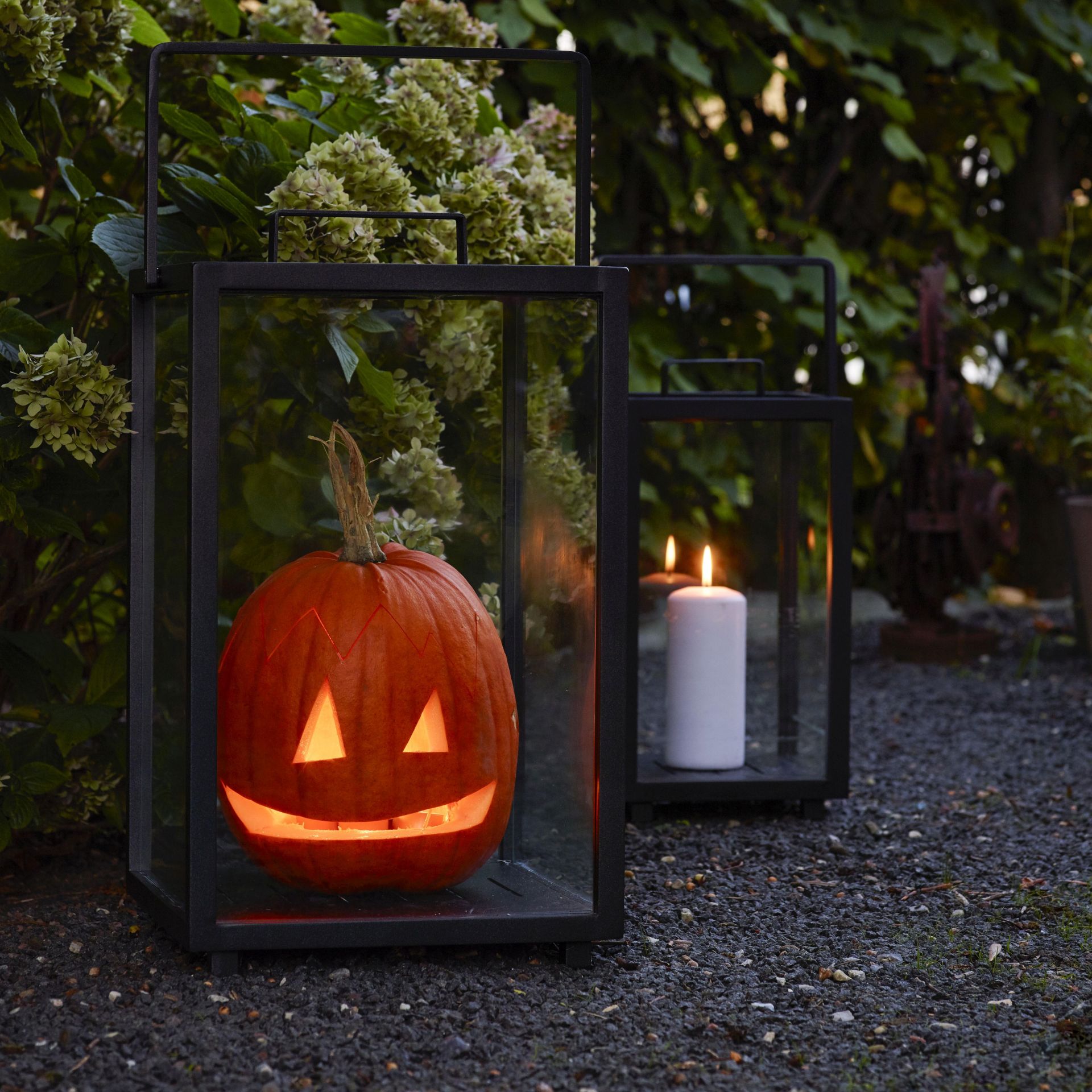 Kleine Cane-Line Lighthouse Aluminium Laterne mit Kürbis und Kerze für Halloween Dekoration im Garten.