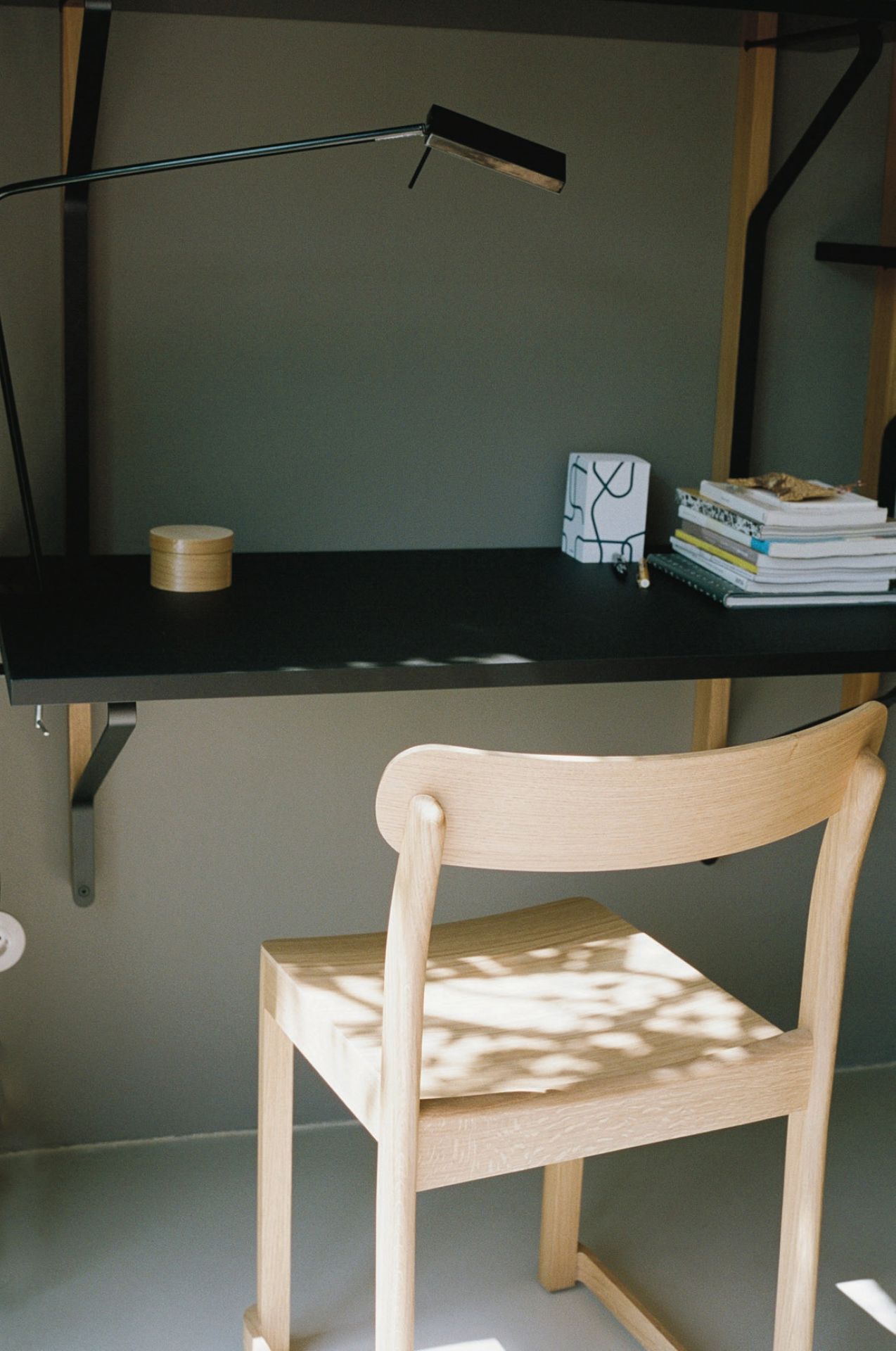 Nahaufnahme des hellen Artek Atelier Chair Stuhls aus Holz an einem Schreibtisch.