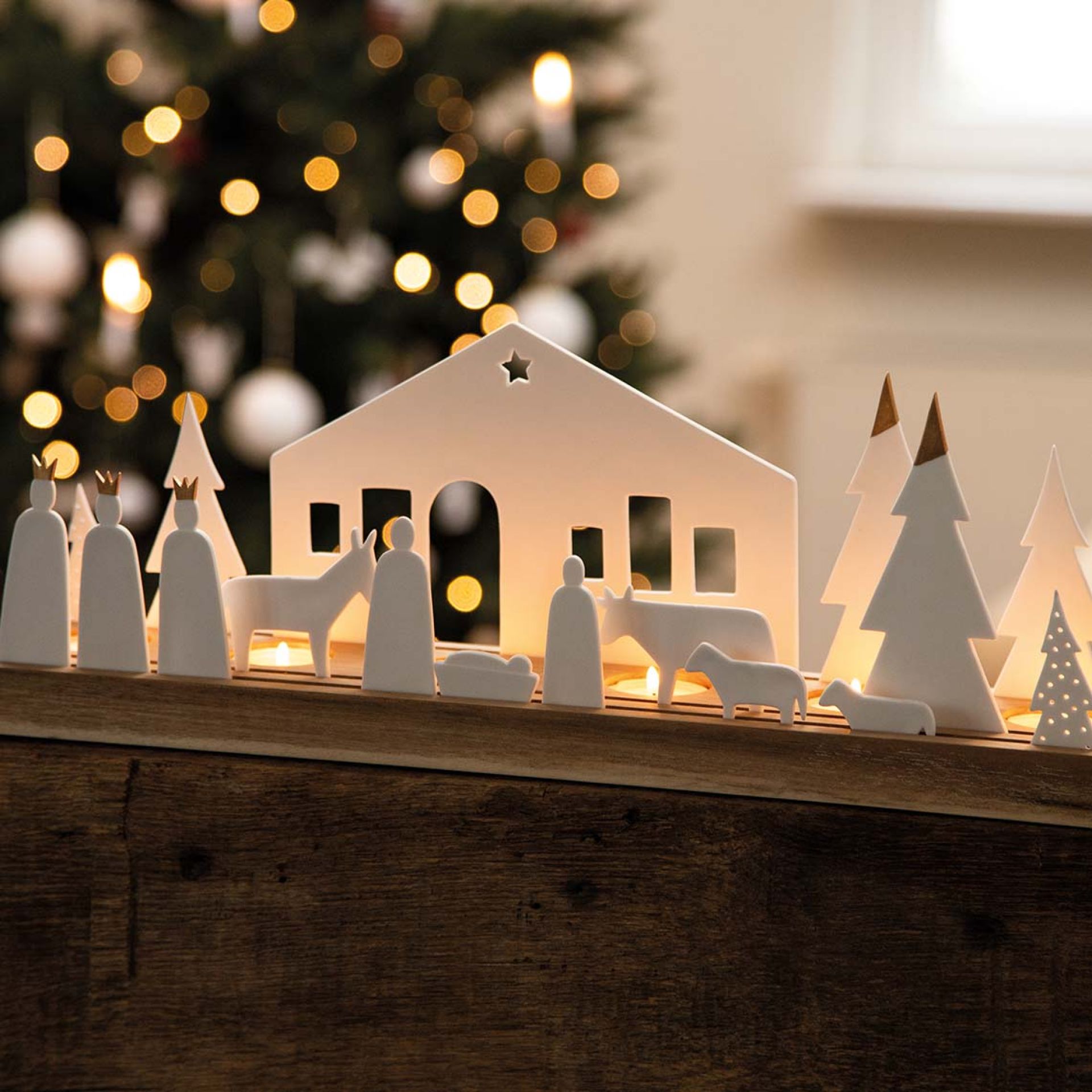 Living Xmas Krippe Lichtobjekt: Weihnachtliche Dekoration mit Figuren, Stall und Bäumen, beleuchtet für stimmungsvolle Atmosphäre.