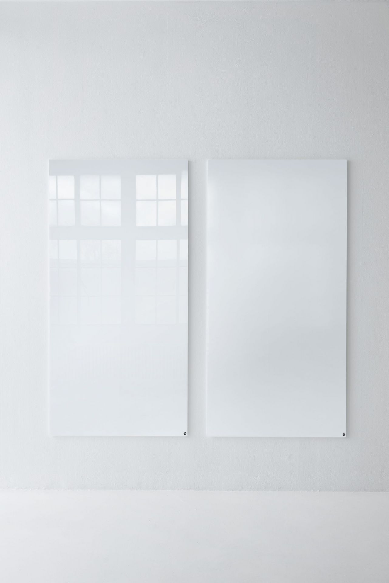 Zwei weiße, magnetische Chat Board Classic Glastafeln hängen an einer weißen Wand im minimalistischen Büro.