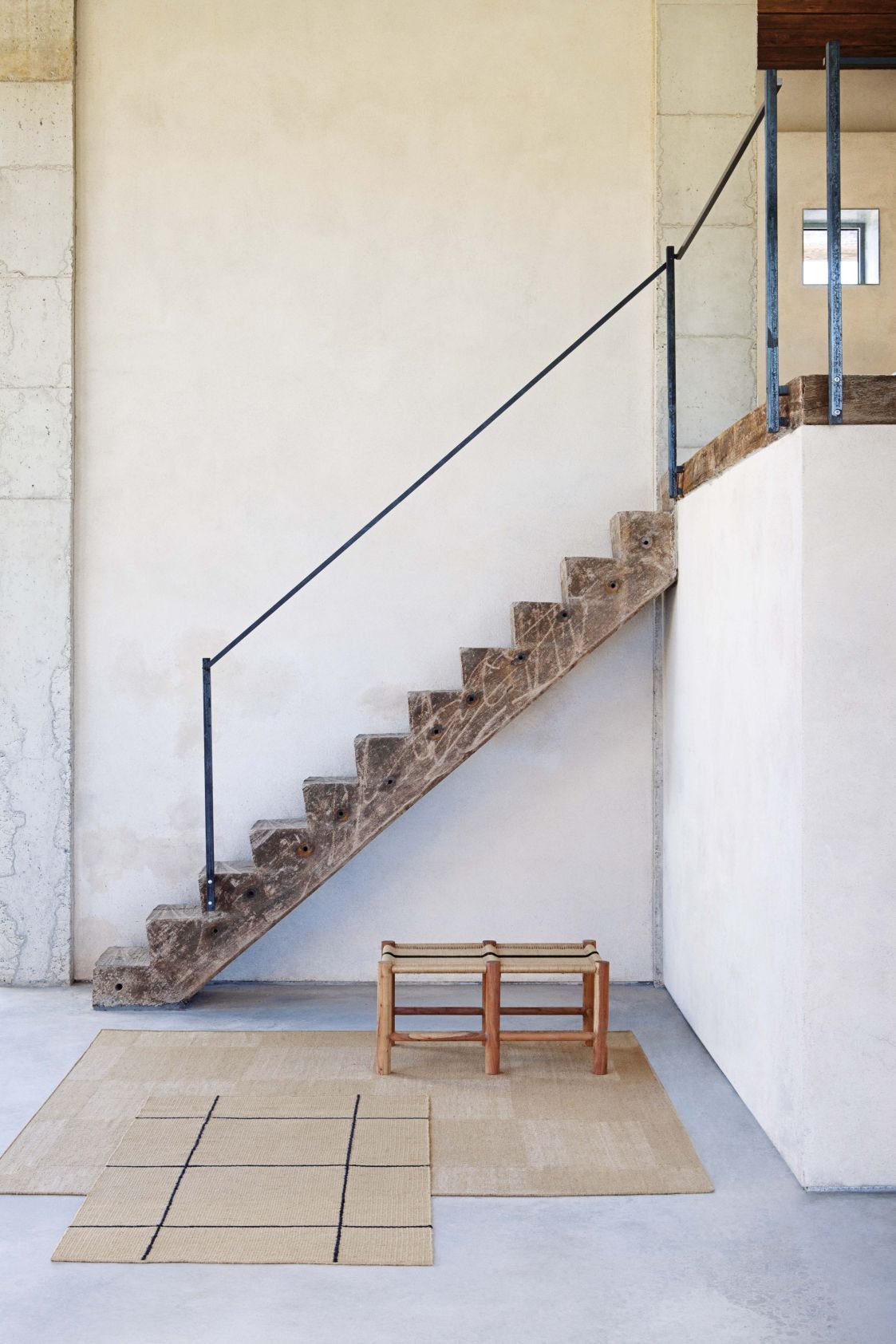 Roots Doppelbank Hocker von Gan vor Treppe und Teppich in minimalistischem Interieur.