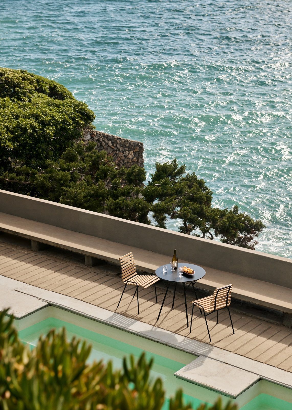 RFH Robin Day RD4 Outdoor Dining Chair von AndTradition auf Terrasse mit Meerblick und Pool.