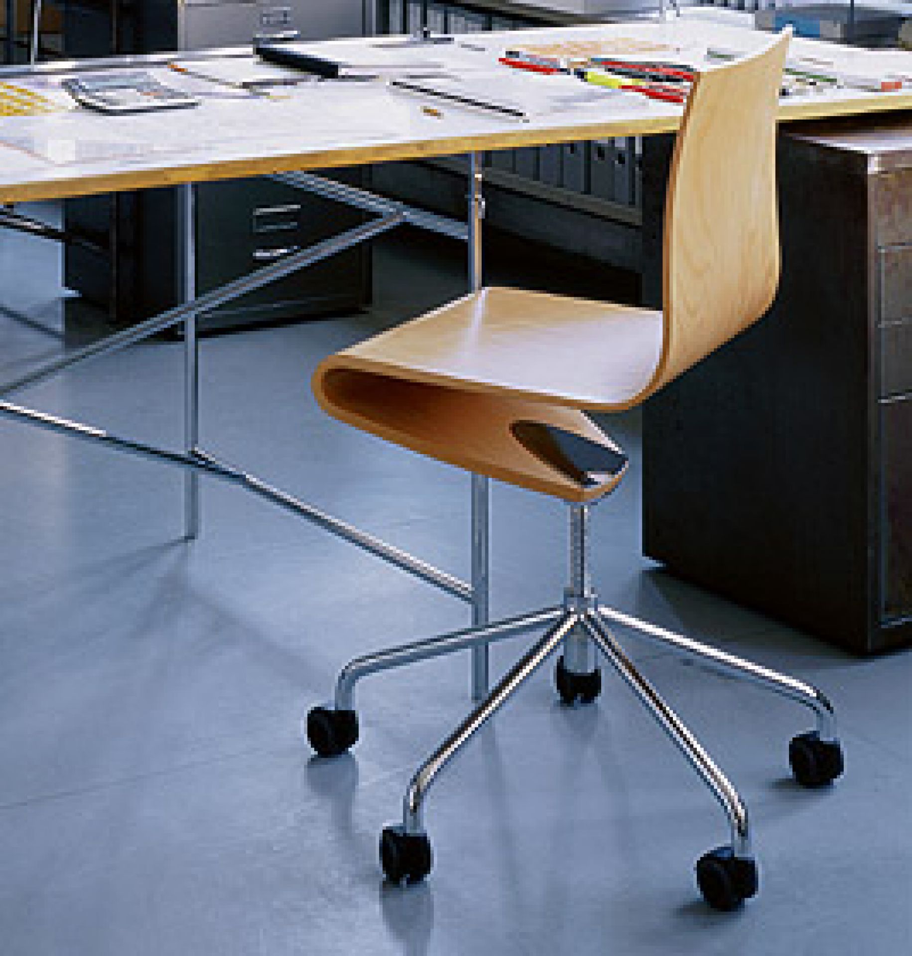 Holz Bürostuhl mit Rollen und Chromgestell vor Schreibtisch, ergonomischer Schreibtischstuhl für modernes Büro.