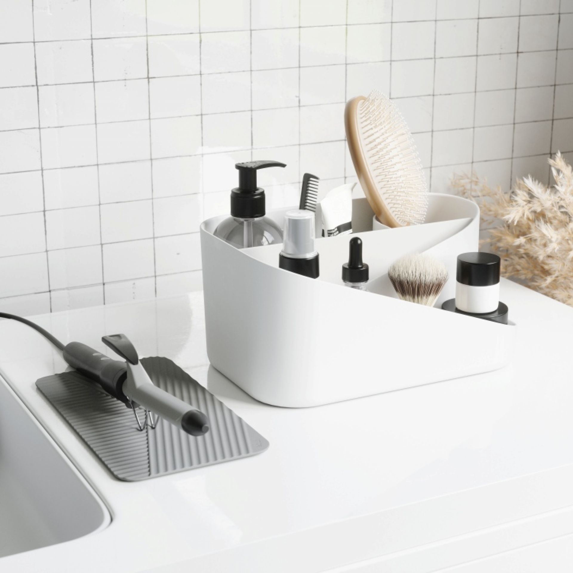 Weißer Glam Hair Organizer von Umbra mit Haarbürste, Kosmetikprodukten und Lockenstab auf weißer Oberfläche.