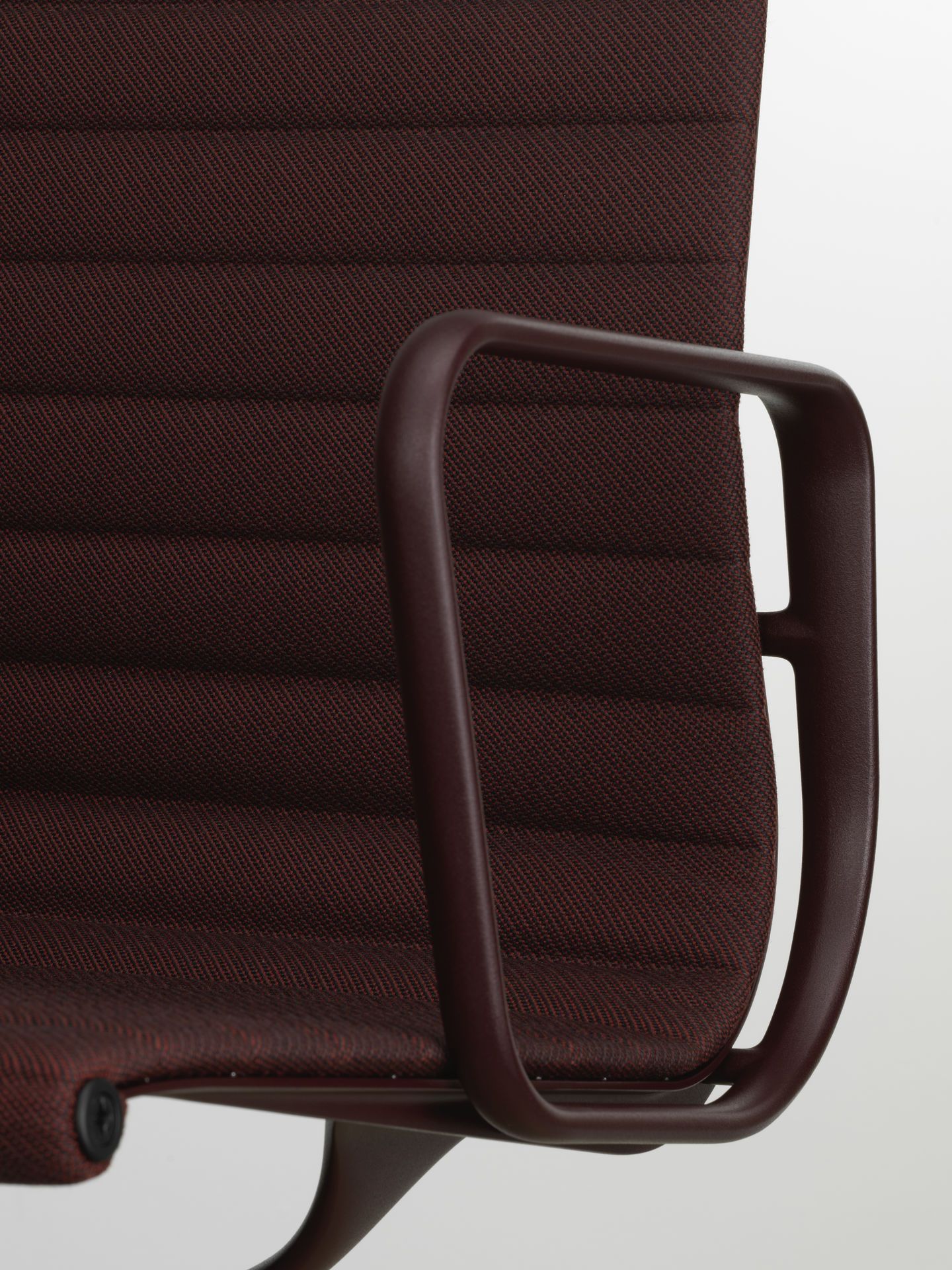 Detailaufnahme vom braunen Vitra EA 108 Aluminium Chair mit Armlehne und Stoffbezug.