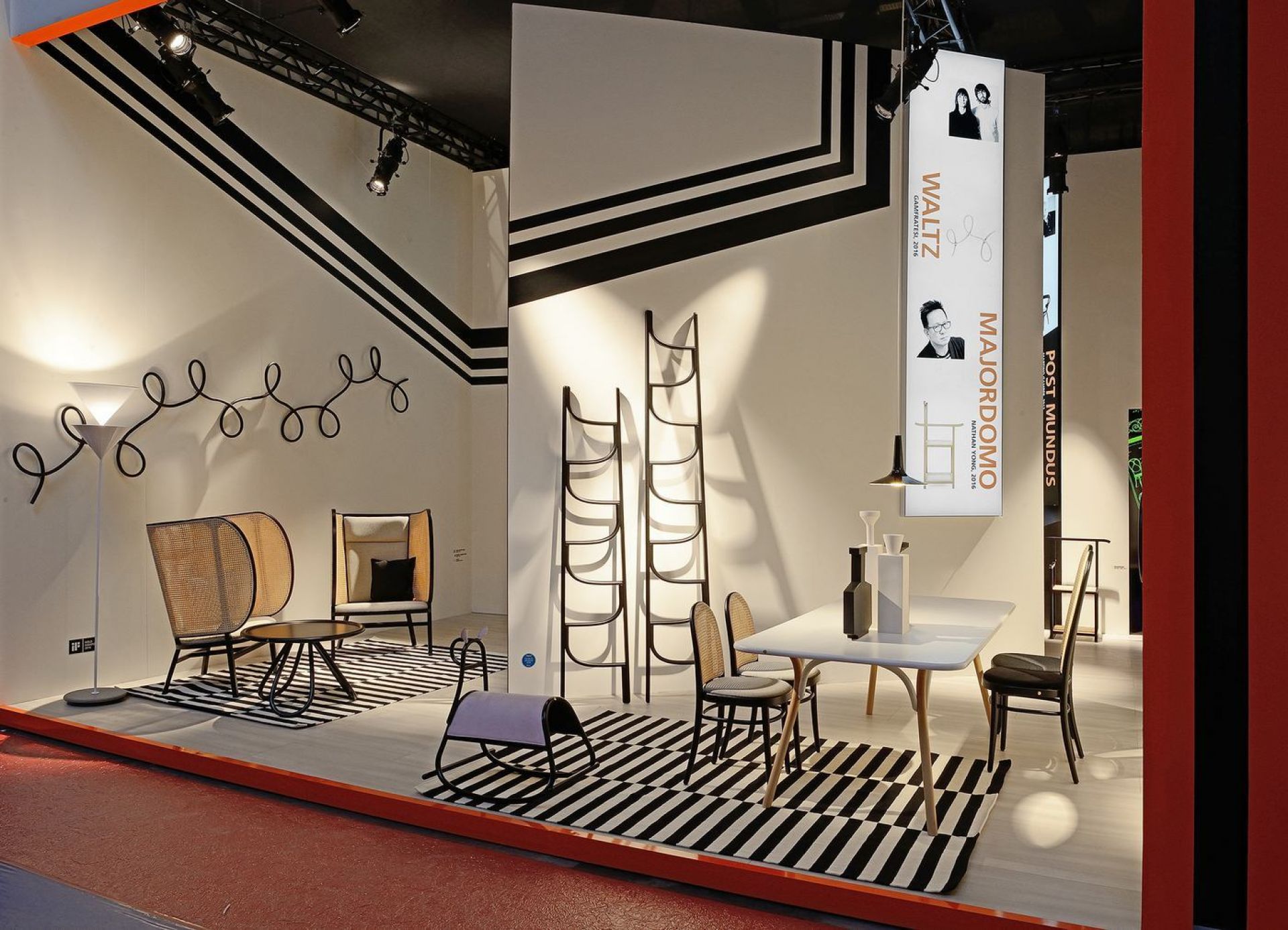 Ausstellungsraum mit Hideout Lounge Chair Sessel von Wiener GTV Design, Rattansessel und modernen Möbeln auf gestreiftem Teppich.