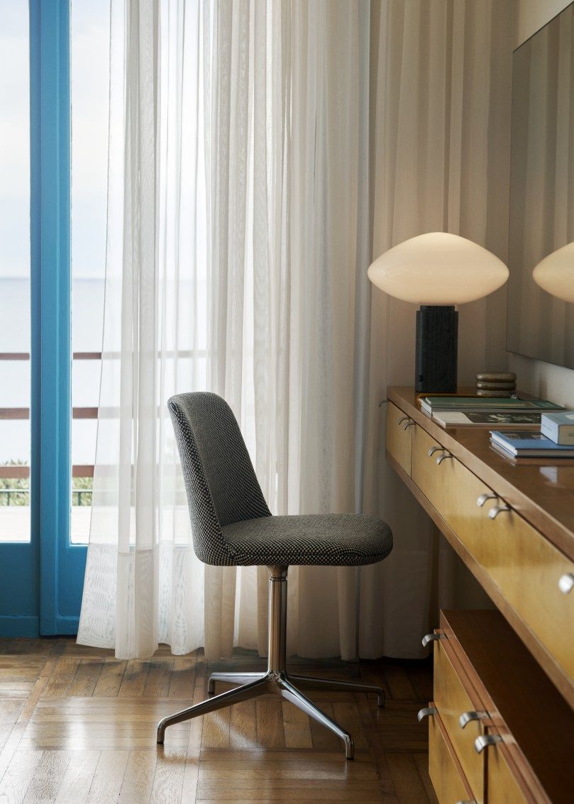 AndTradition Mist AP17 Tischleuchte Guatemale Verde auf einem Schreibtisch, neben einem Fenster mit Vorhängen.