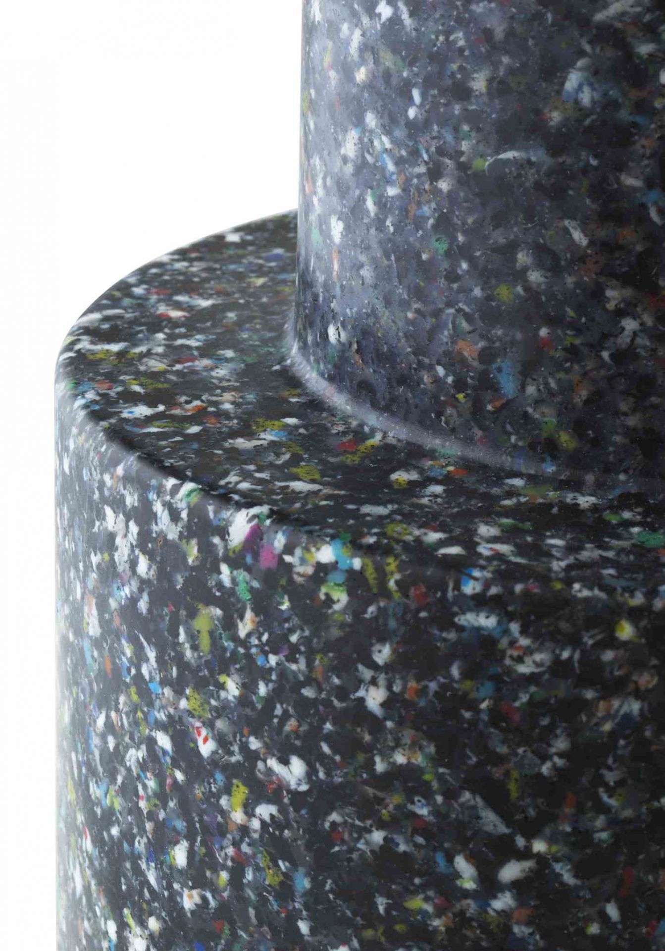 Detailaufnahme des Normann Copenhagen Bit Stool Hockers in dunklem Recycling-Kunststoff mit bunten Sprenkeln.