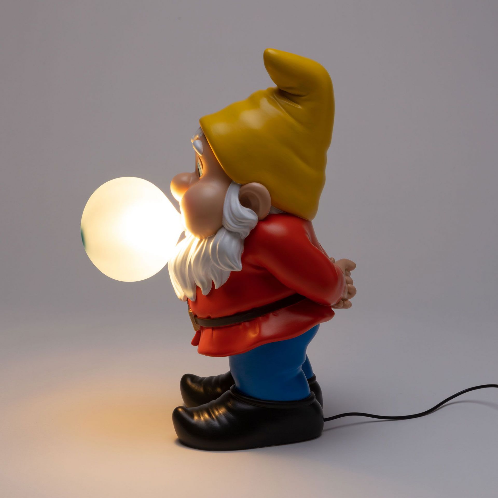 Seletti Gummy Snooping Leuchte: Detailaufnahme einer Zwergenlampe mit gelber Mütze und leuchtender Kugel.