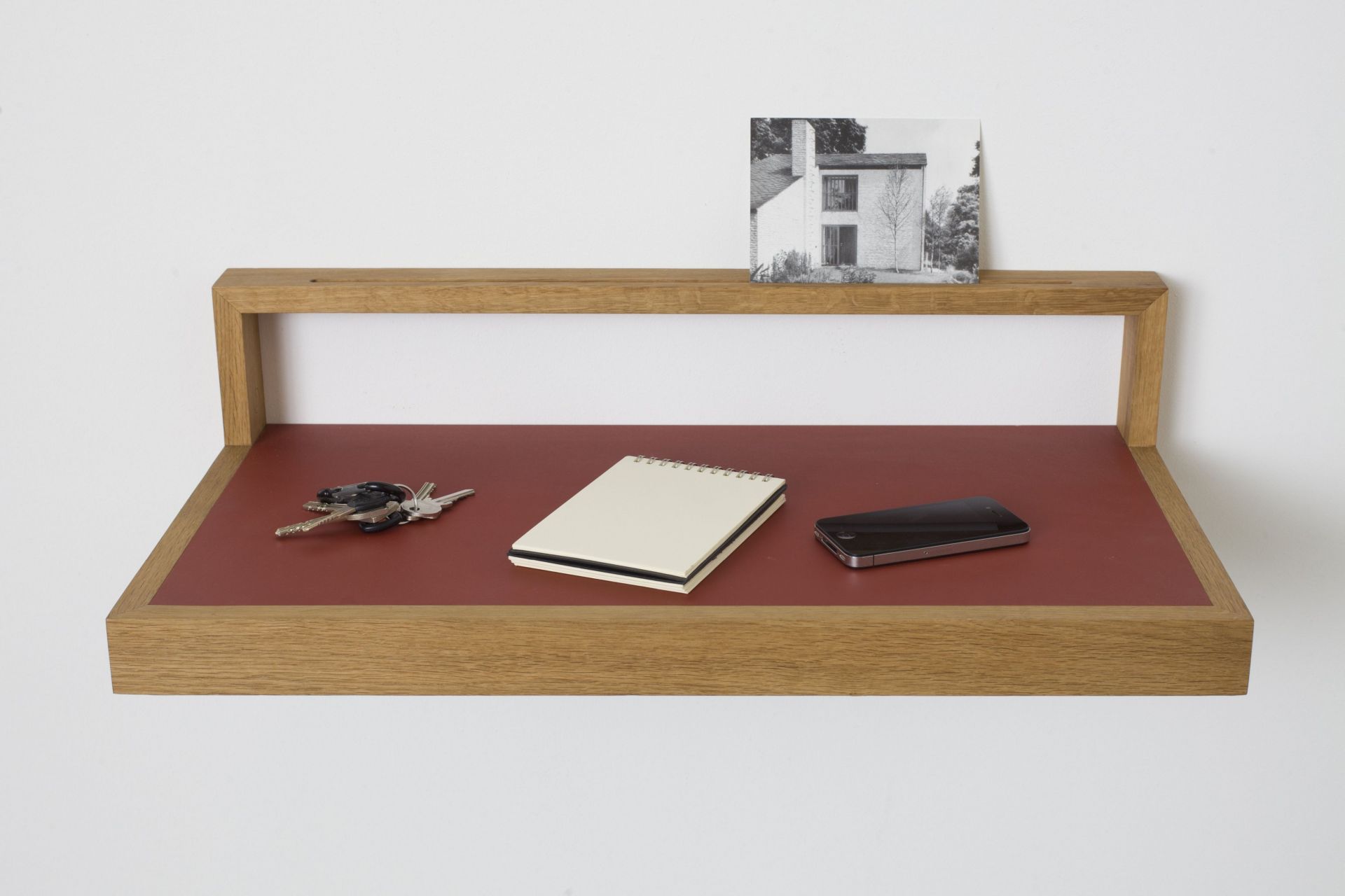 Ablageboard "buck" aus Holz mit Schlüssel, Notizblock und Smartphone auf roter Ablagefläche.