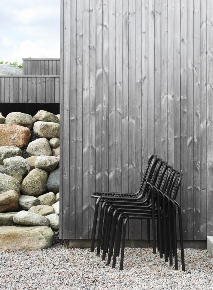 Stapel schwarzer Vig Chair Stühle von Normann Copenhagen für den Außenbereich vor Holzwand.