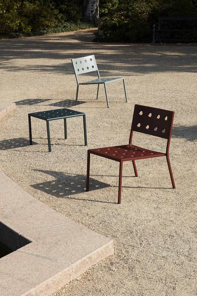 Hay Balcony Lounge Chair und Beistelltisch für den Außenbereich in Grau und Rotbraun auf Kies.