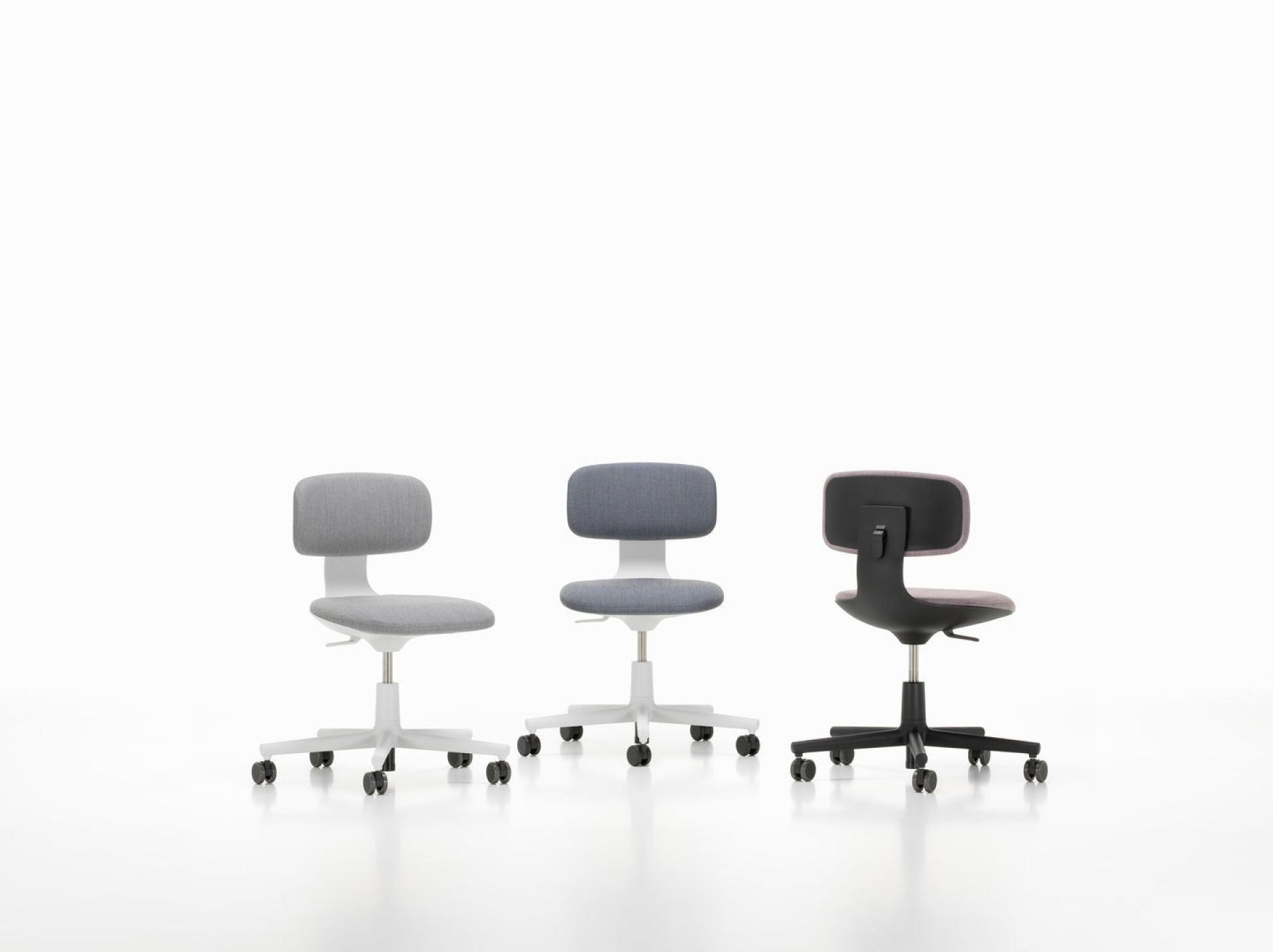 Drei Vitra Rookie Bürodrehstühle in Grau und Schwarz mit Rollen vor einem weißen Hintergrund.