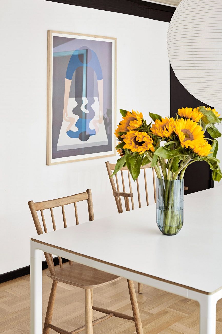 J41 Stuhl von Hay aus Holz an Esstisch mit Sonnenblumen in Vase.
