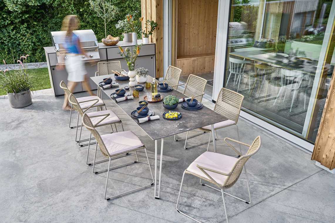 Slope Tisch von Weishäupl, ein moderner Esstisch für den Außenbereich mit Stühlen und Geschirr.
