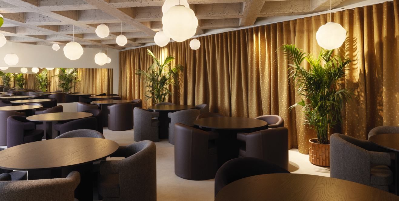 Innenraumansicht eines Restaurants mit mehreren Bubba Pendelleuchten von Normann Copenhagen, die von der Decke hängen.