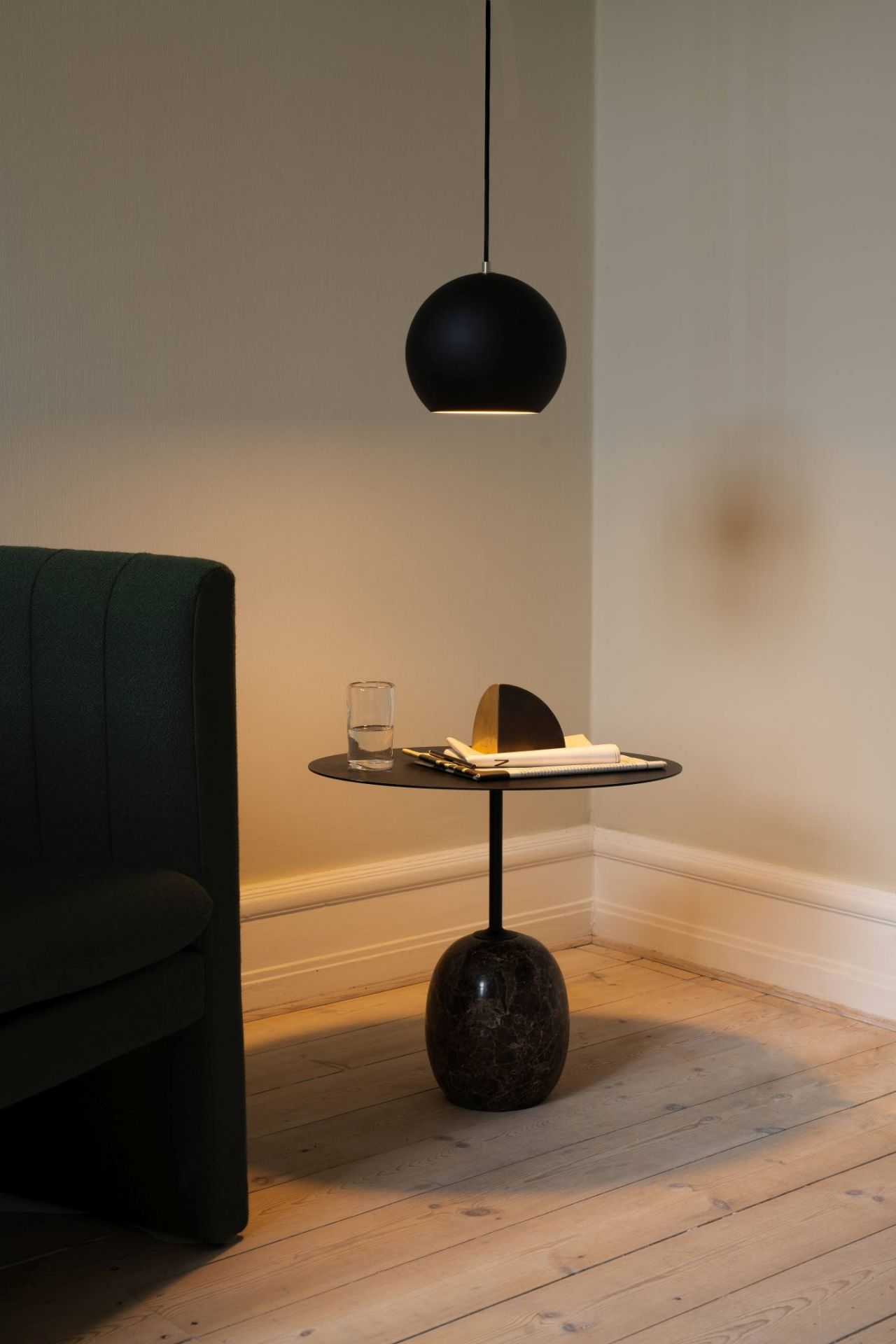 Schwarze Topan Hängeleuchte von AndTradition über einem Beistelltisch mit Dekoration in einem stilvollen Interieur.