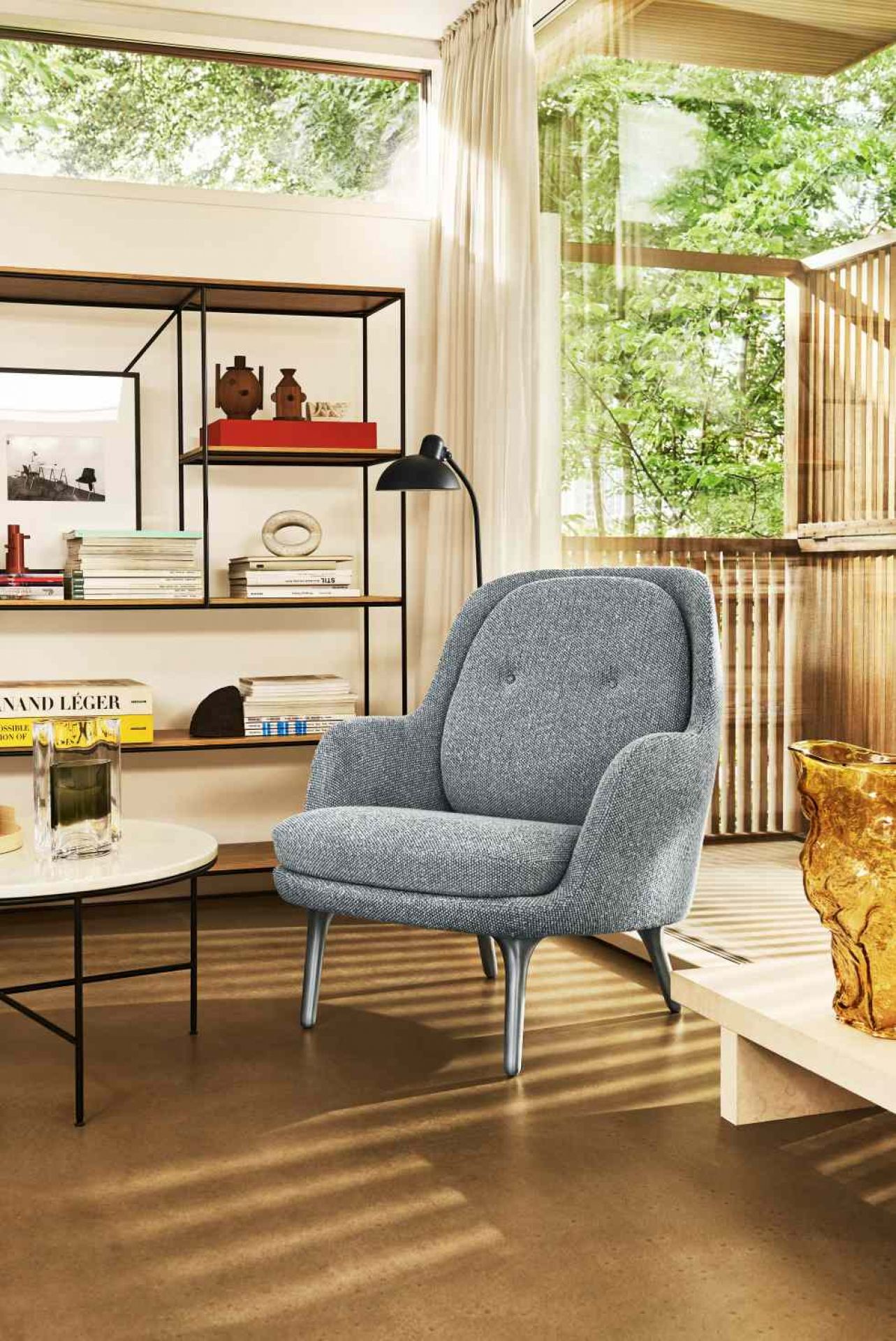 Grauer Fri Sessel von Fritz Hansen im modernen Wohnzimmer mit Bücherregal und Fenster.